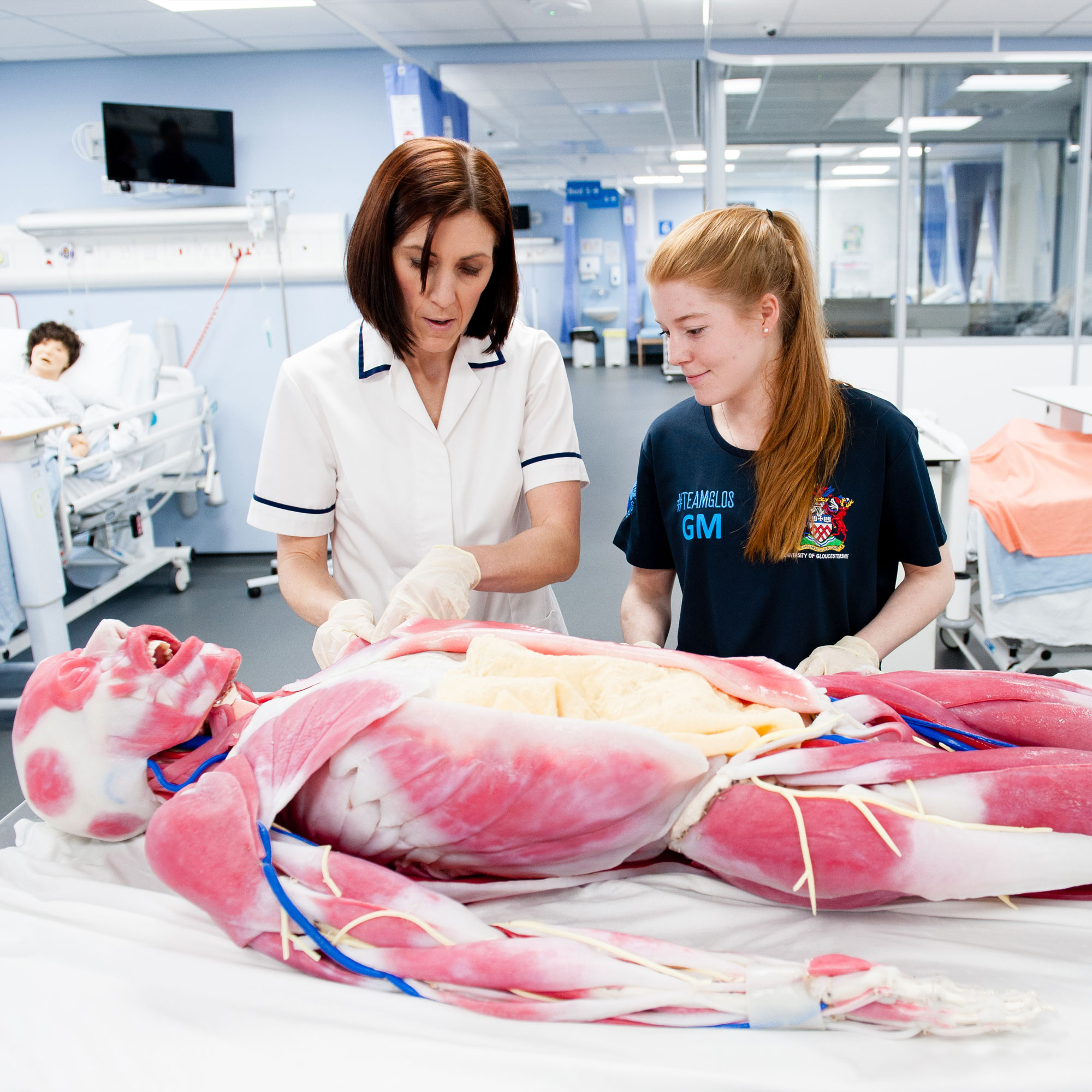 Physiotherapy lecturer and student looking at model of human body