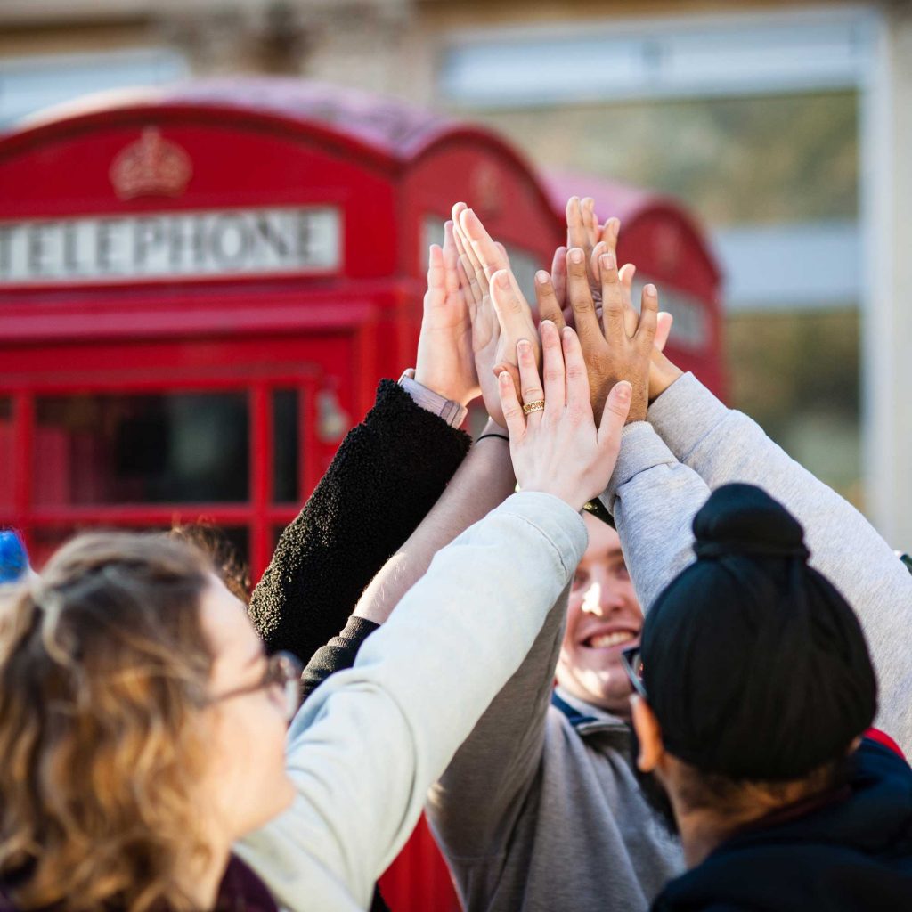 Students celebrating University Clearing results outside telephone box