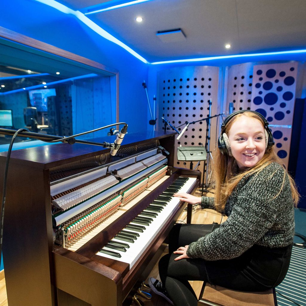 Student at a piano in a recording studio