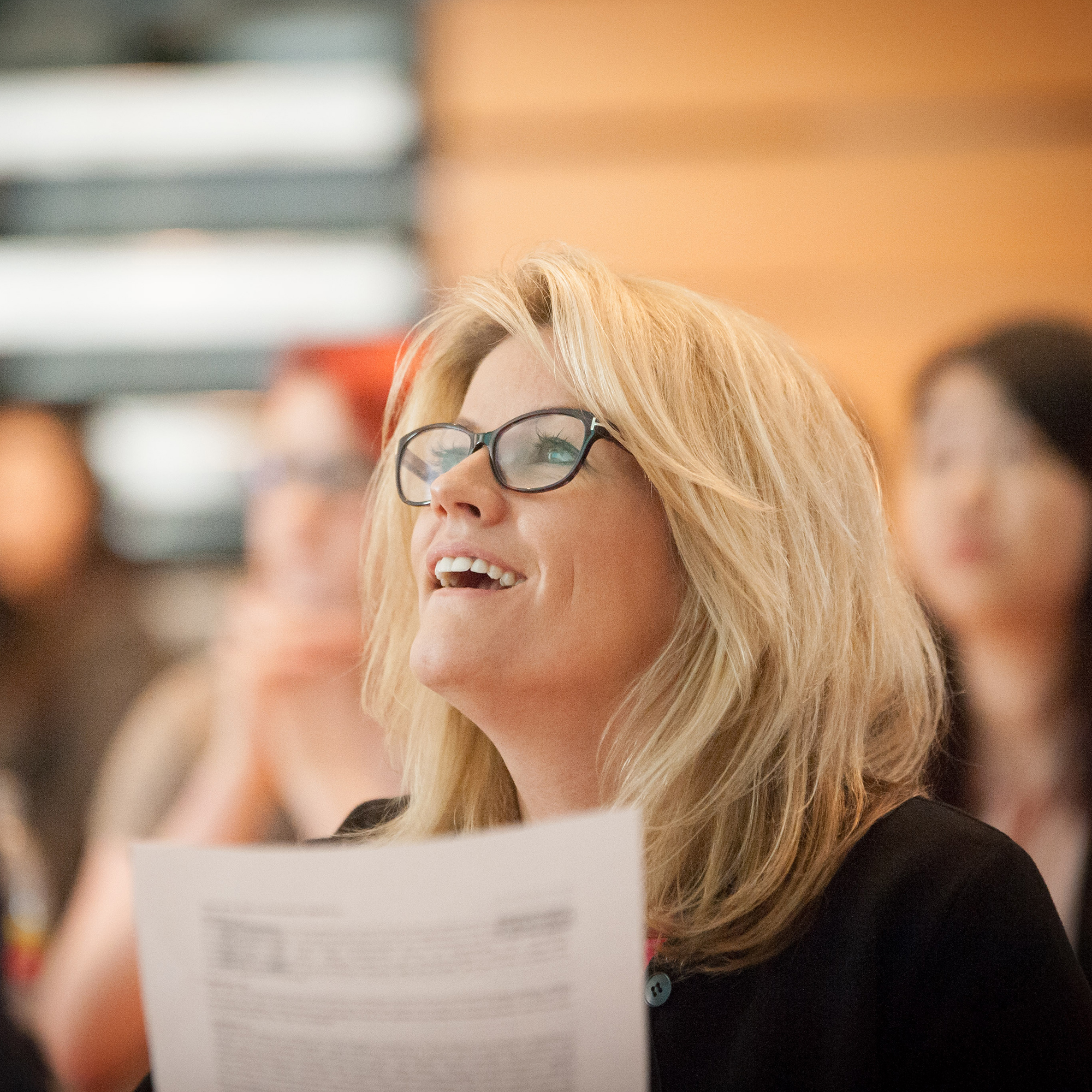 A woman looking up towards someone she's listening to whilst holding a piece of paper