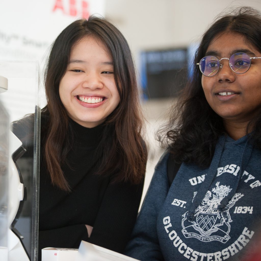 Two students are smiling as they work over a desk