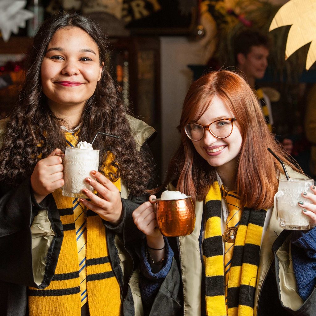 Students dressed up in harry potter costumes drinking butter beer
