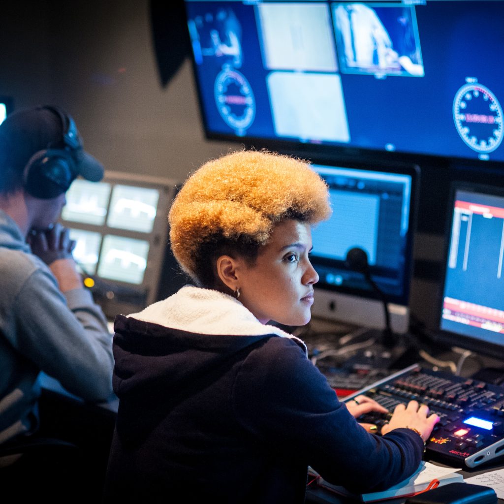 2 people sat in front of screens and computer equipment