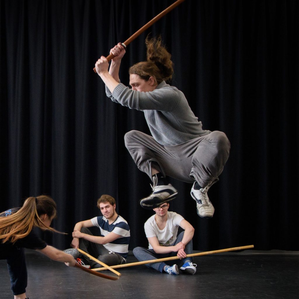Student jumping with stick