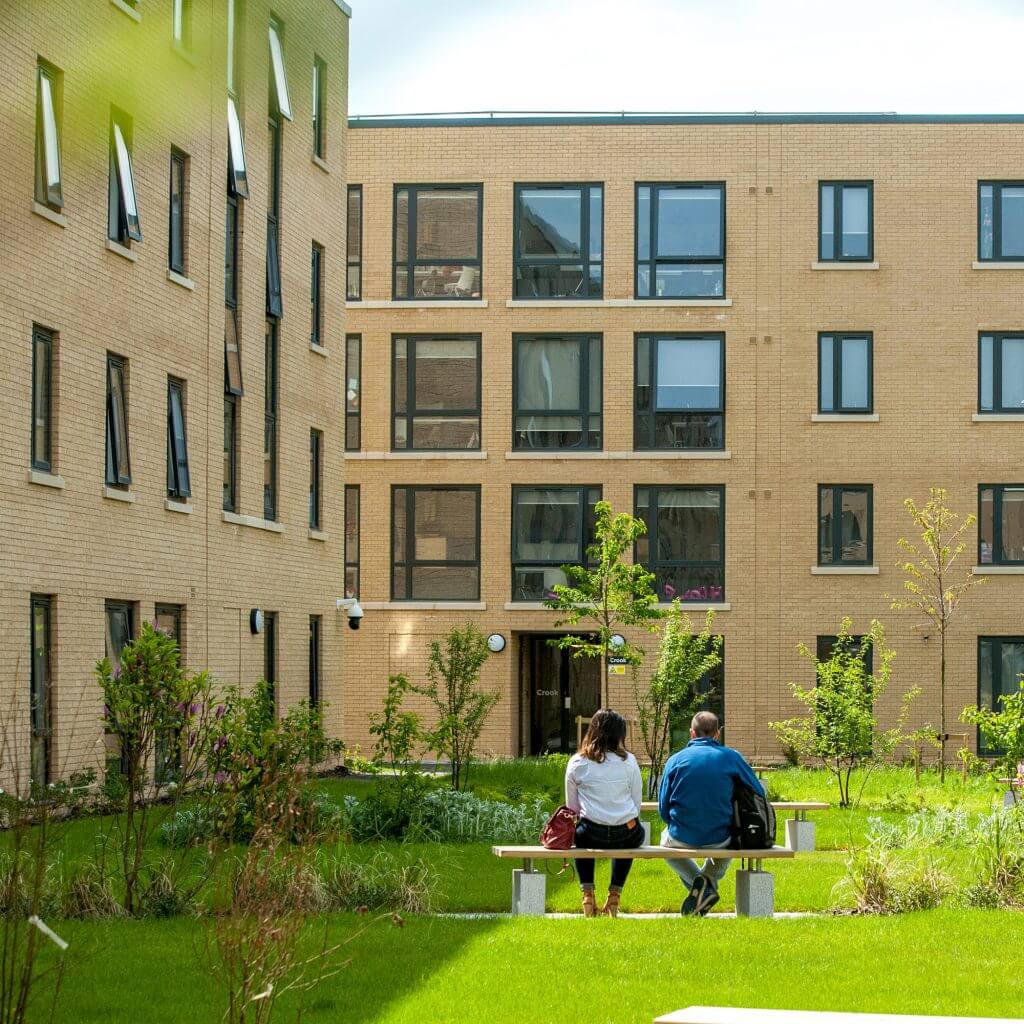 People sat in green space at Pittville Student Village in the sunshine