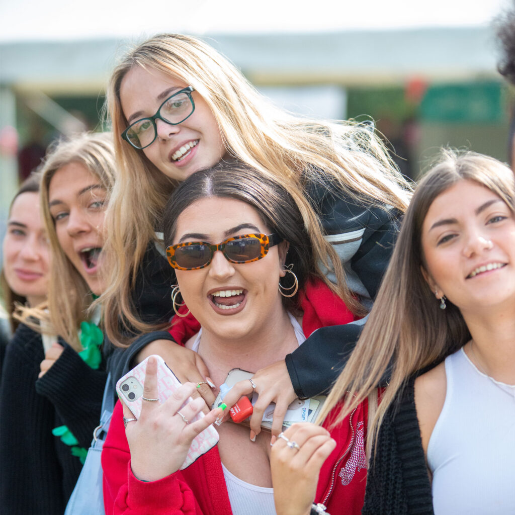 Students outside at UoG Freshers Fayre 2023 smiling with sunglasses on