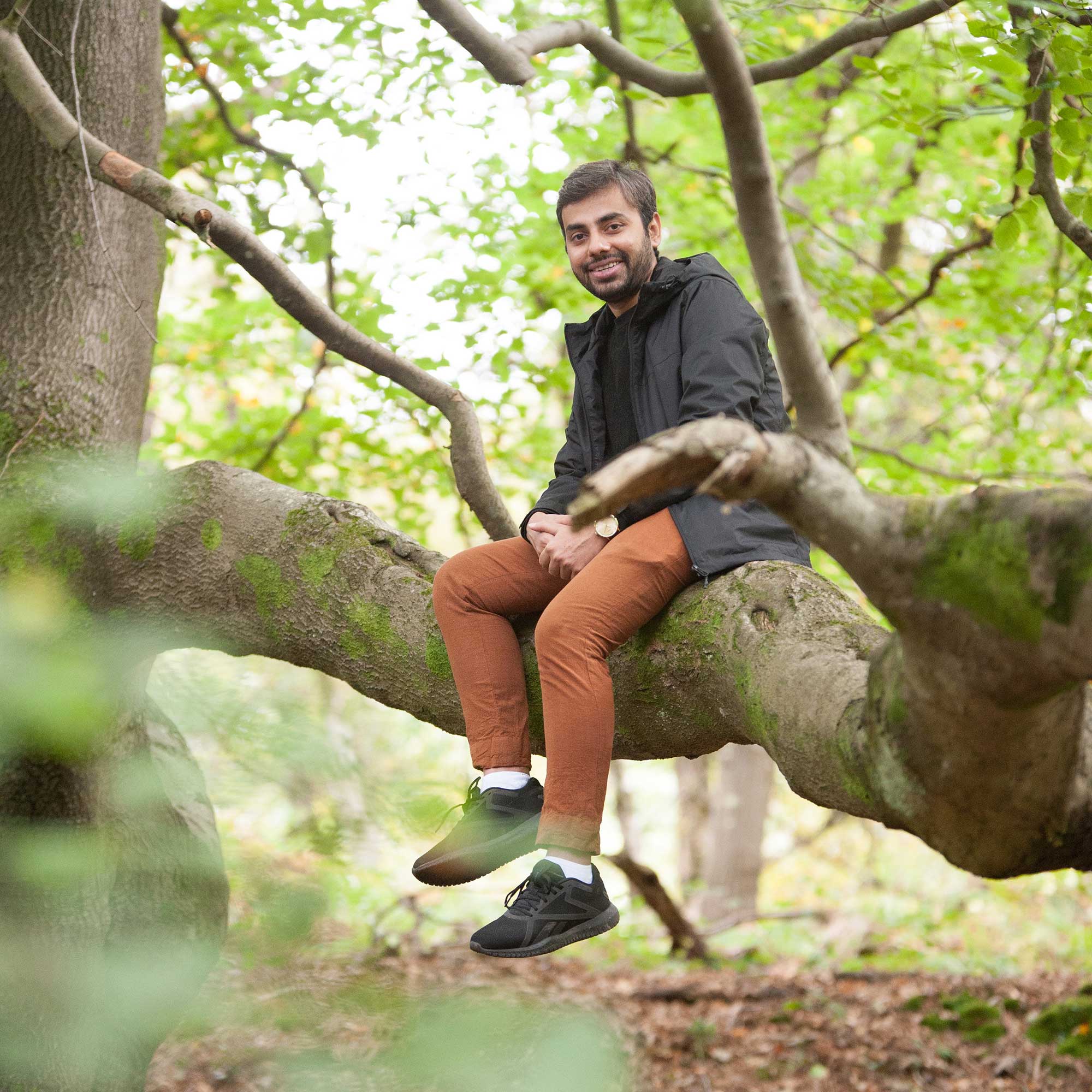 A postgraduate students sits on the tree bough in the Forest of Dean.
