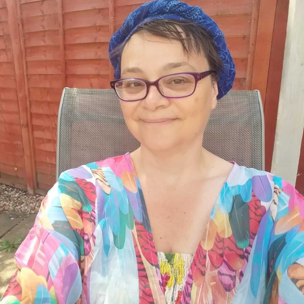 Student Cathy smiling as she sits on a chair in a garden.