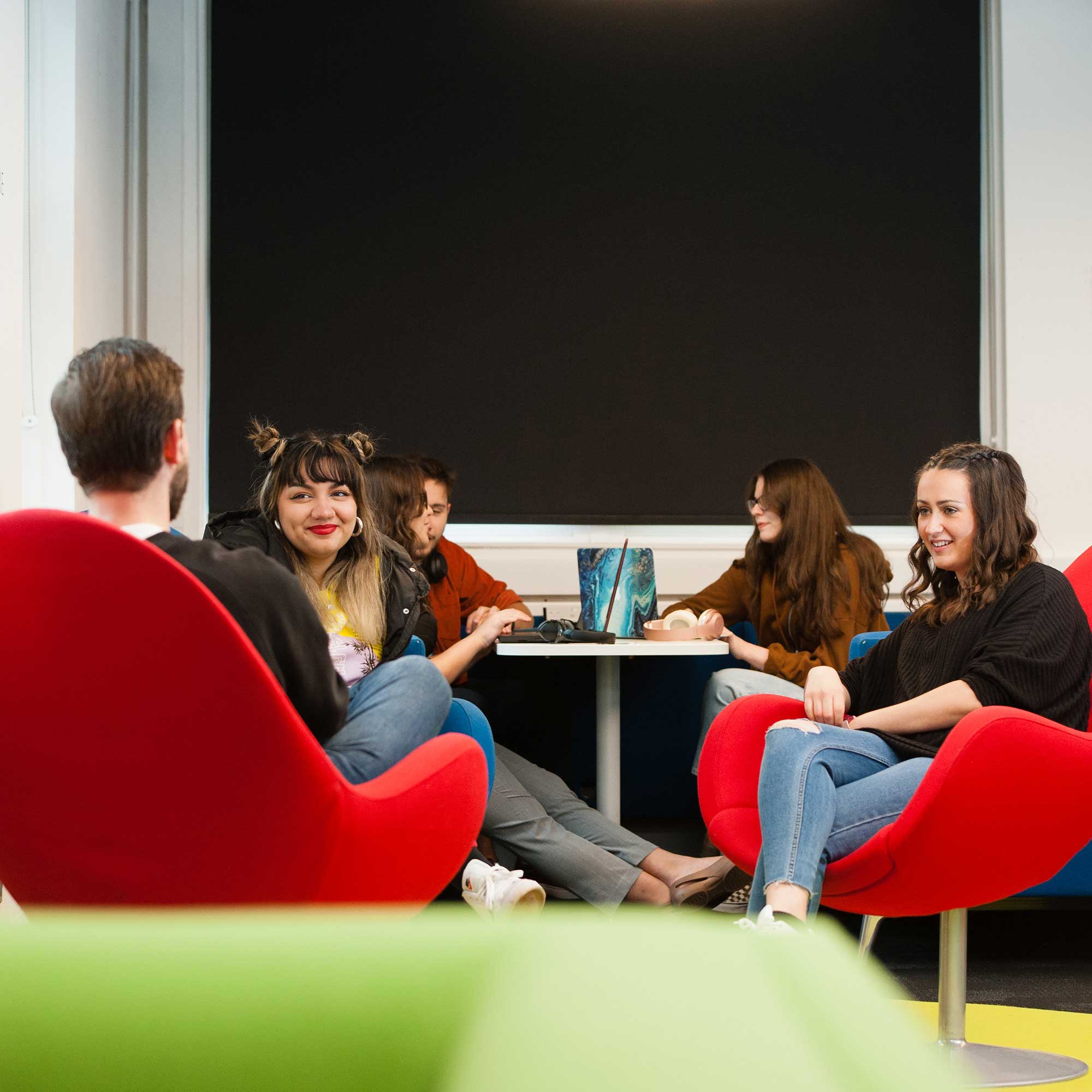 A group of students sit around a table talking.