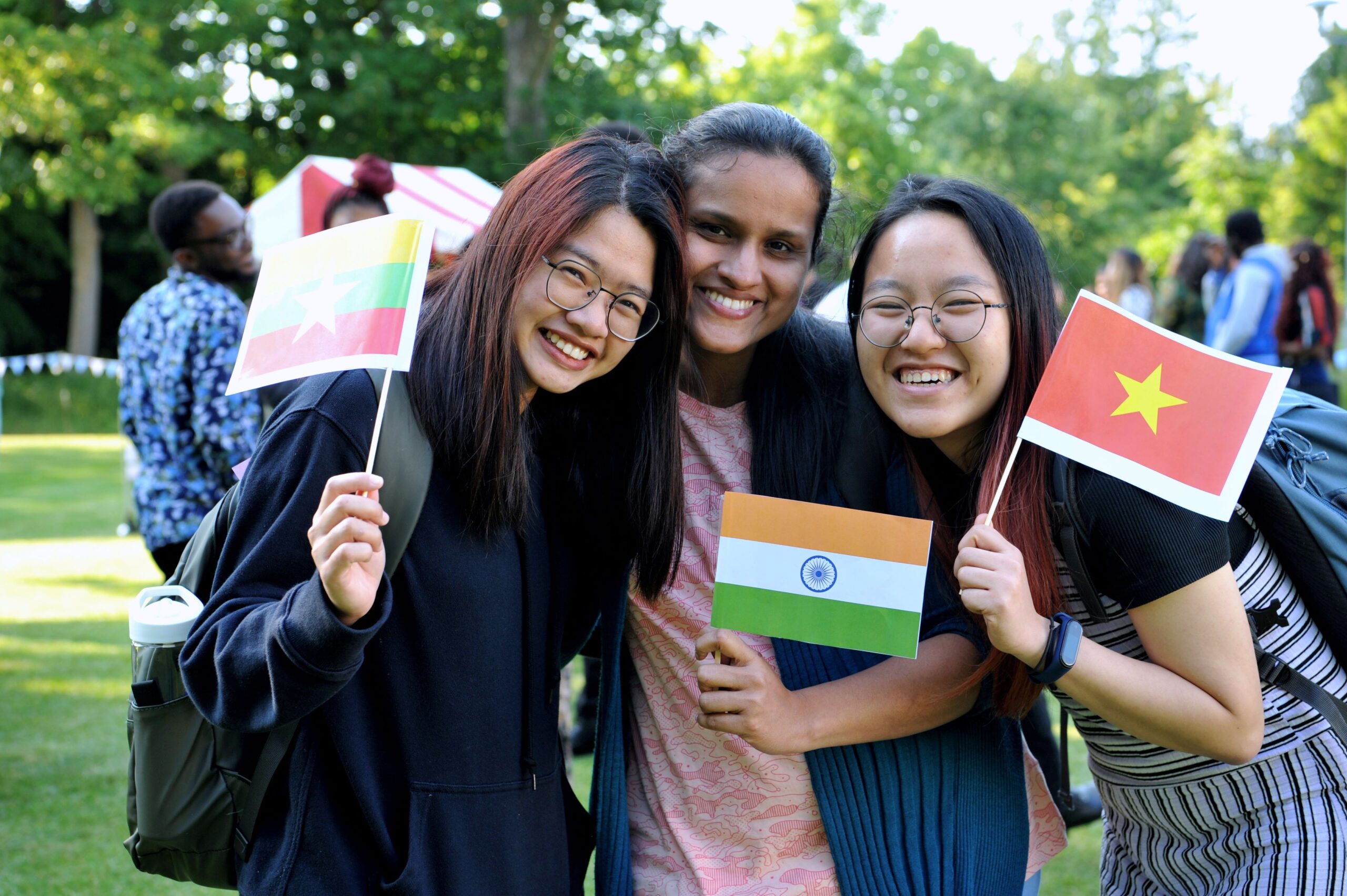 three international students holding small flags