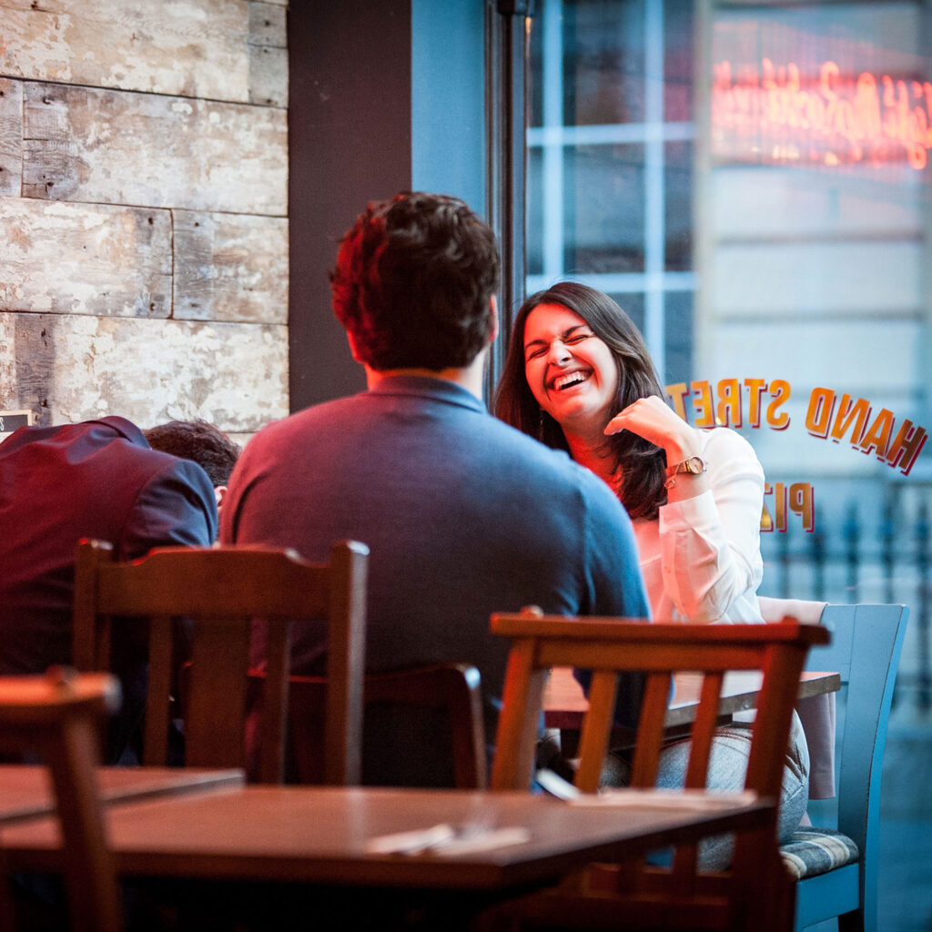 Two people sat at a table in a bar laughing