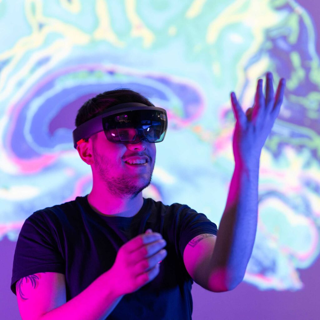 A student wearing a VR headset with a scan of a brain projected behind him.