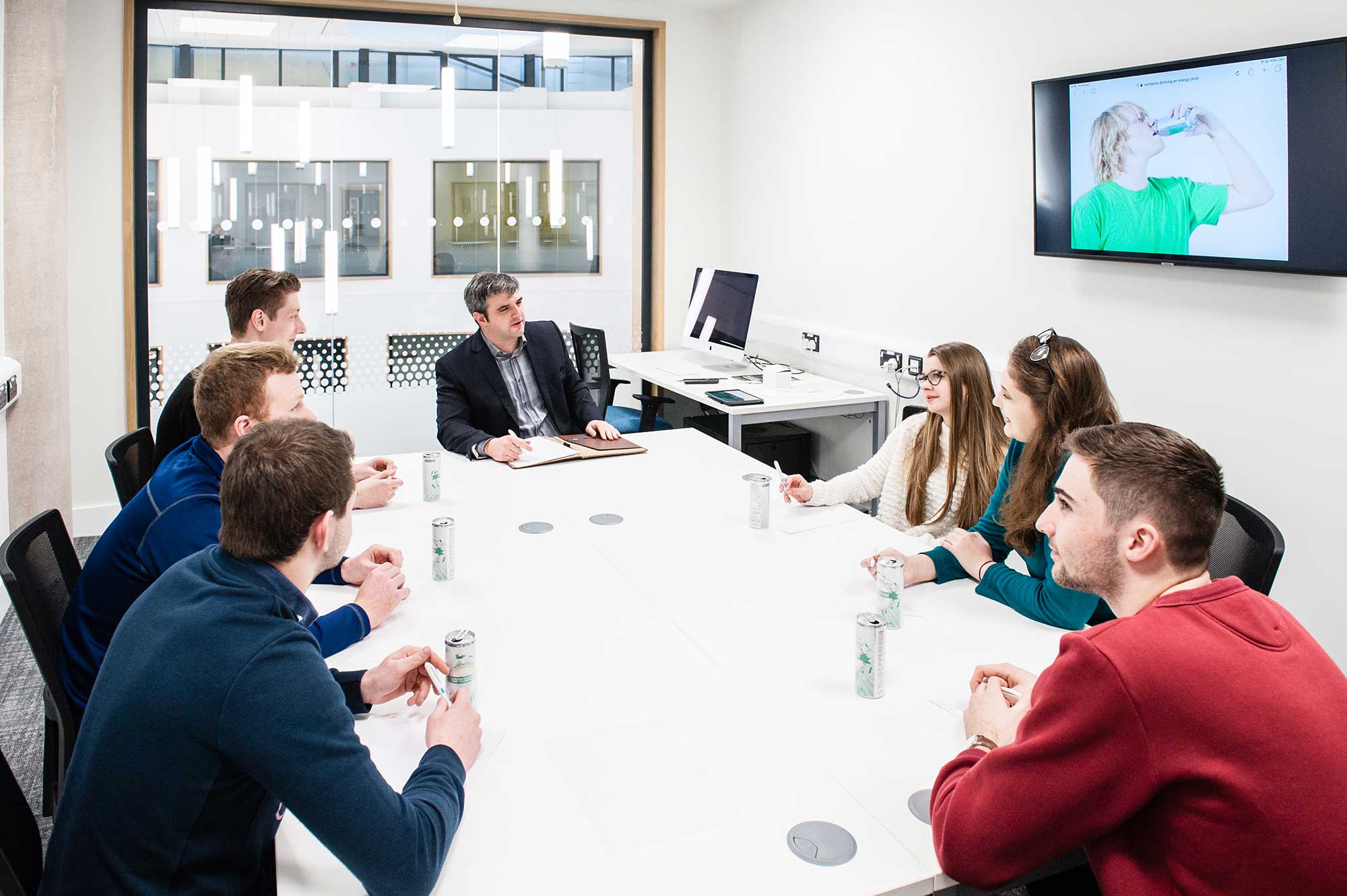 A group of student sit in a meeting room with a lecturer.