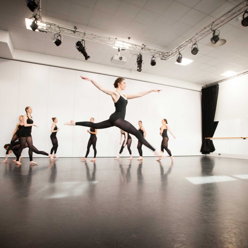 A ballet dancer leaping in the air in the dance studio.