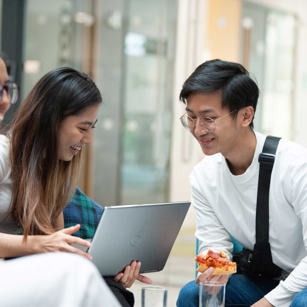Two students look at a laptop together.