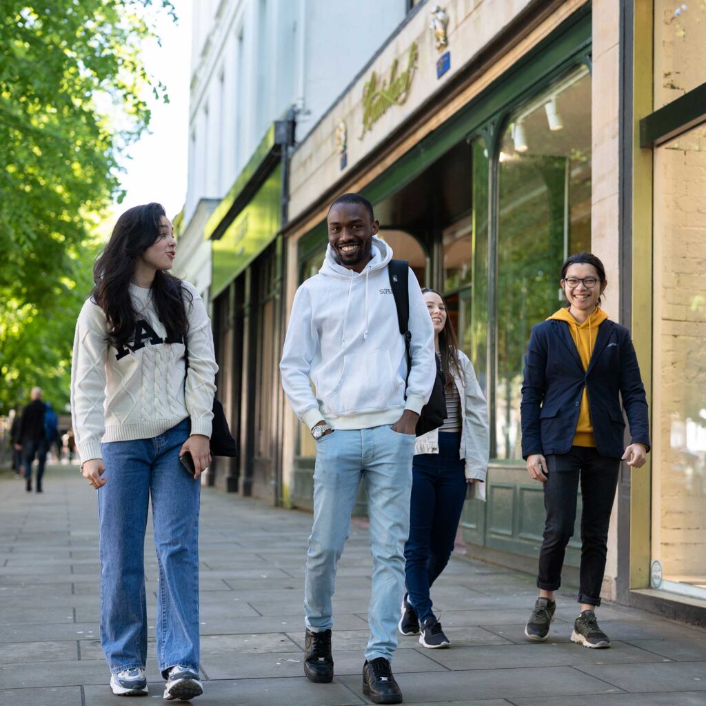 Four students walk along the Promenade in Cheltenham town centre.