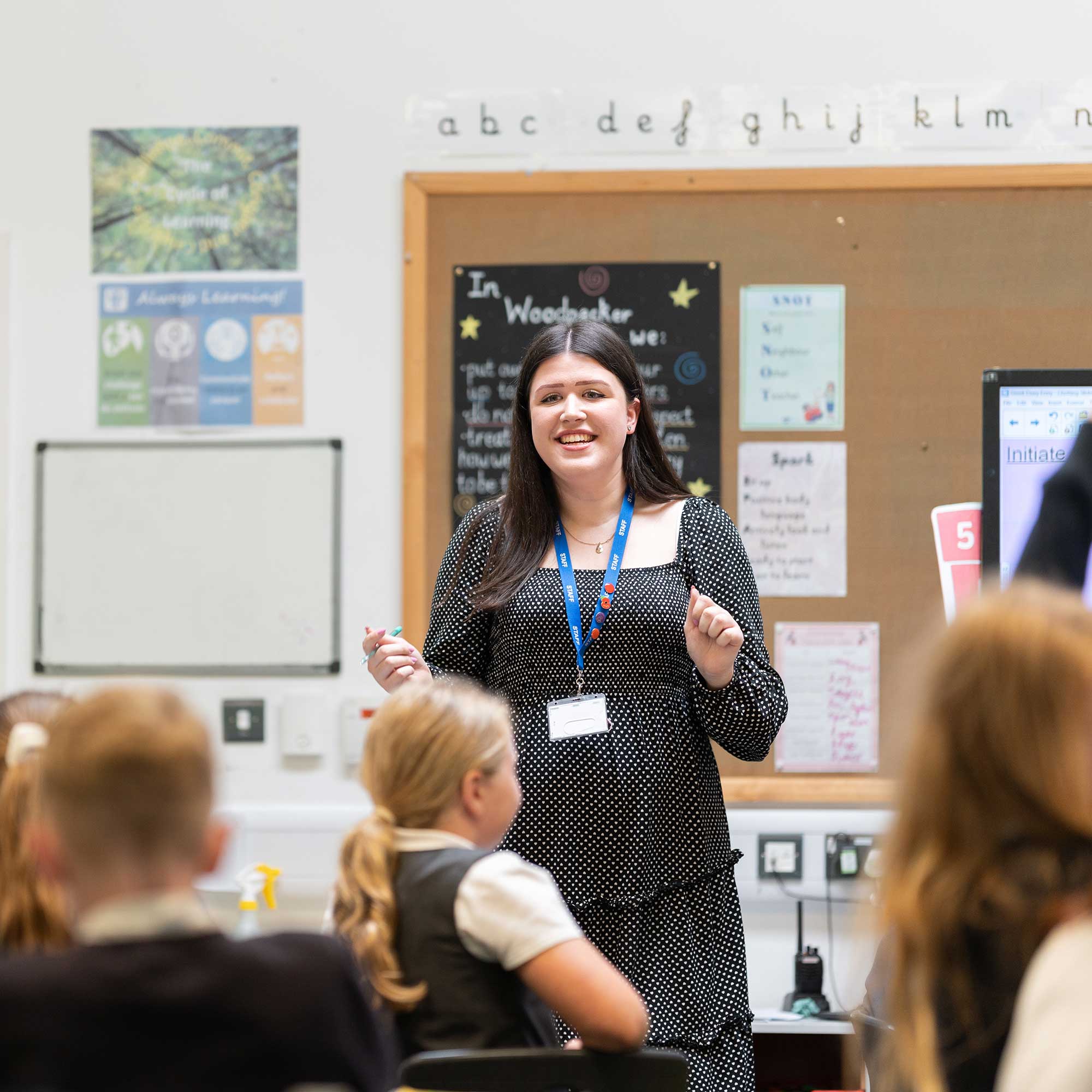 Lauren stands at the front of a class of primary school children.