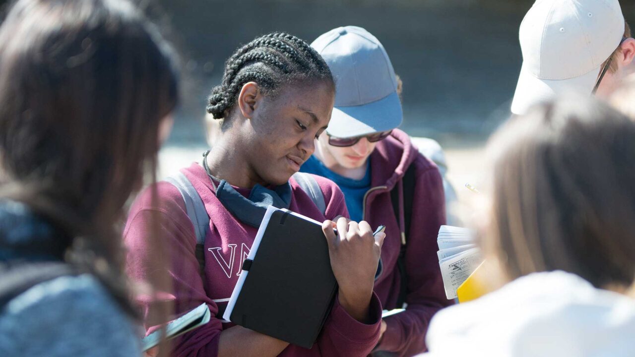 A groups of students on a field trip making notes.