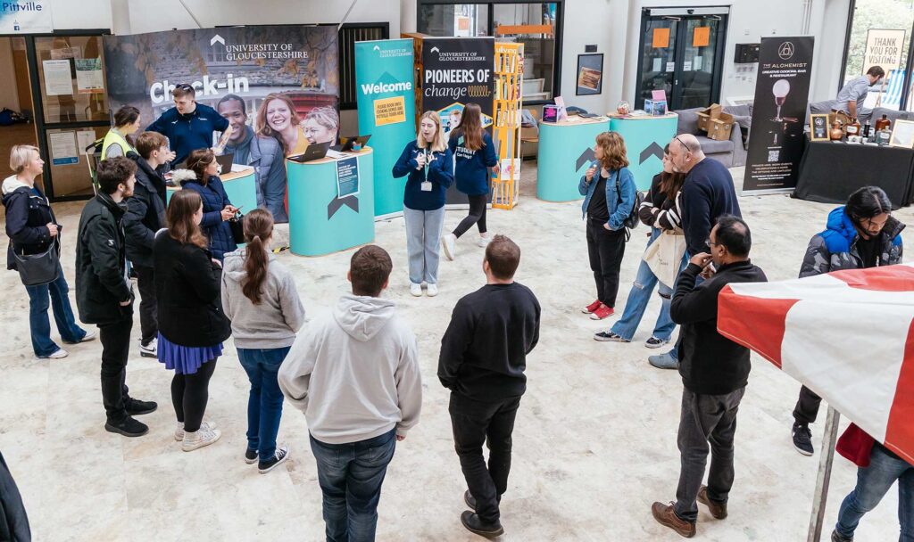 Students attending the Get Uni Ready Open Day listen to a student ambassador speaking in the atrium at Pittville.