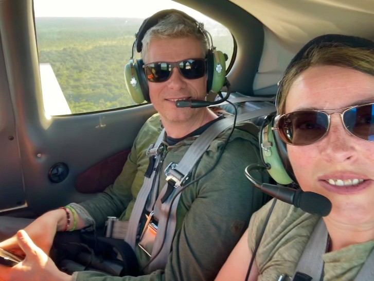 Adam and Anne taking a selfie in a plane with the African bush in the background