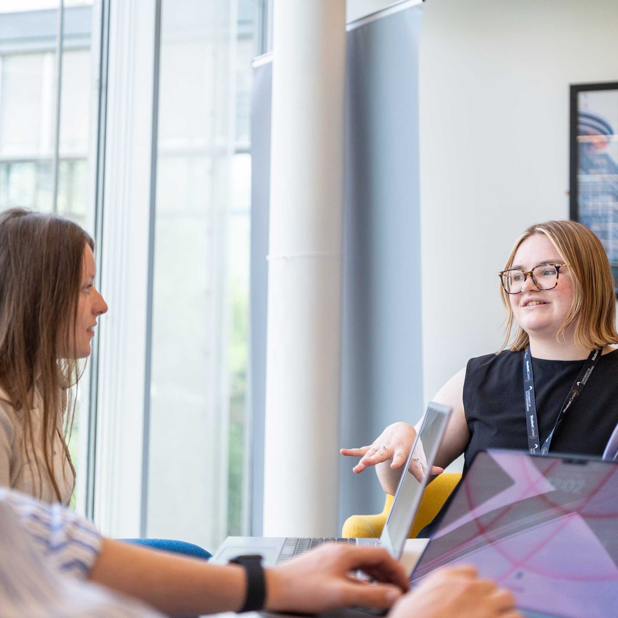 Students chatting to a member of staff within a Student Centre.