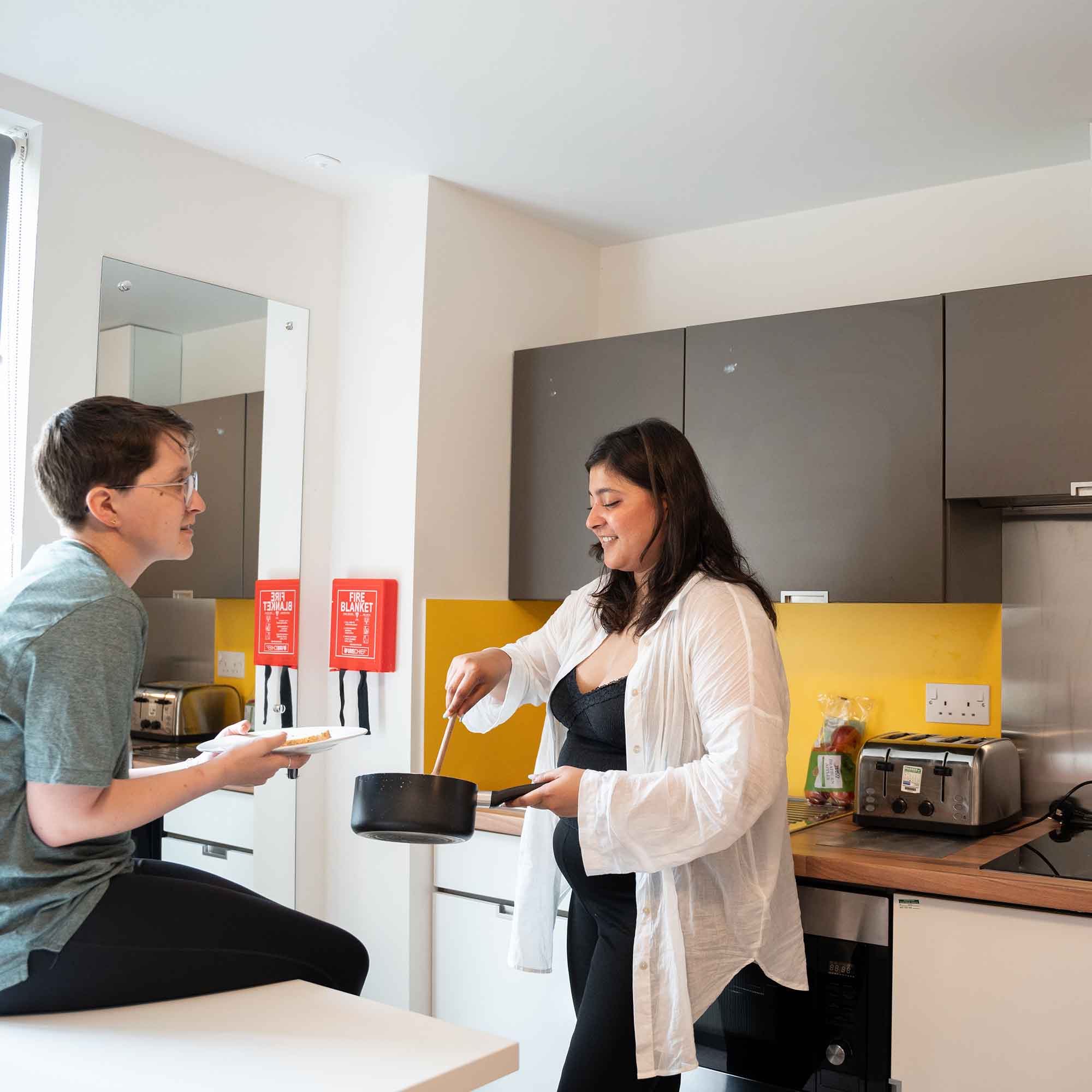 Students serving up food in a halls of residence kitchen.